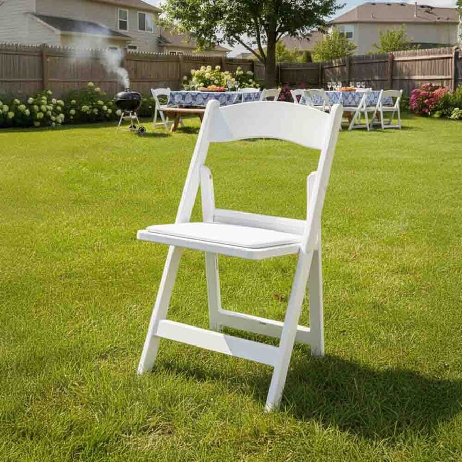 White resin folding chair on a backyard lawn