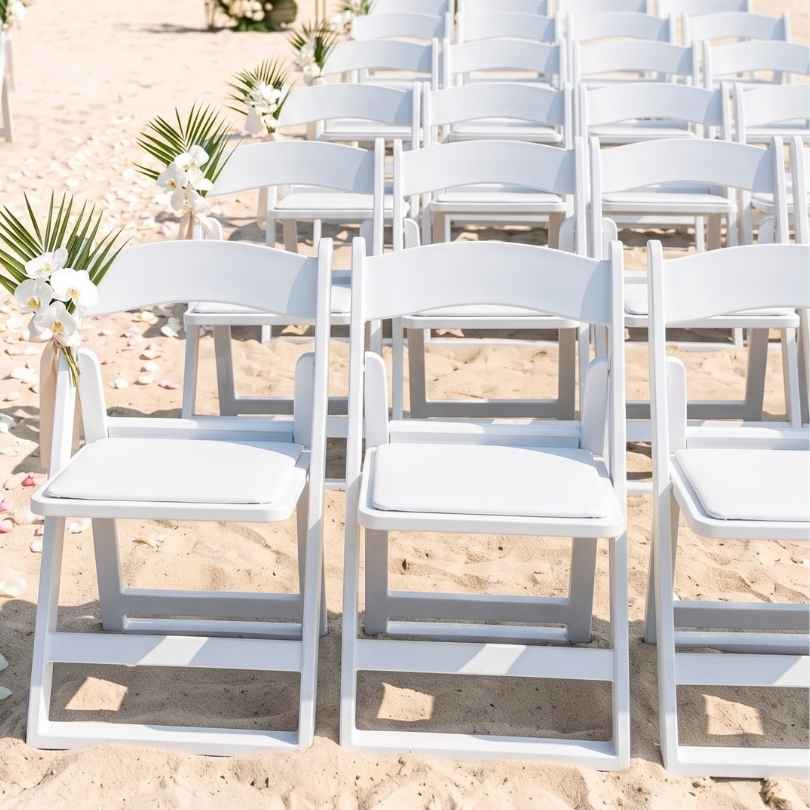Rows of white Grass and Sand chairs set for a beach ceremony