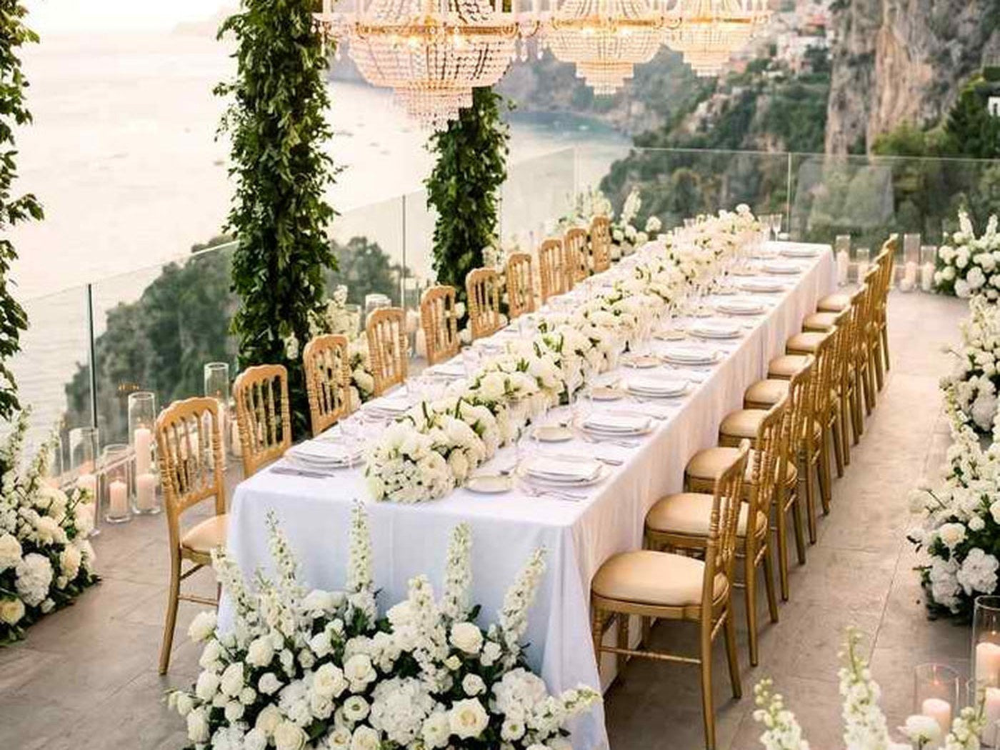 The same chair on a long table under greenery. At 36 inches tall it holds a vertical line down the length of the table without crowding the centerpieces.