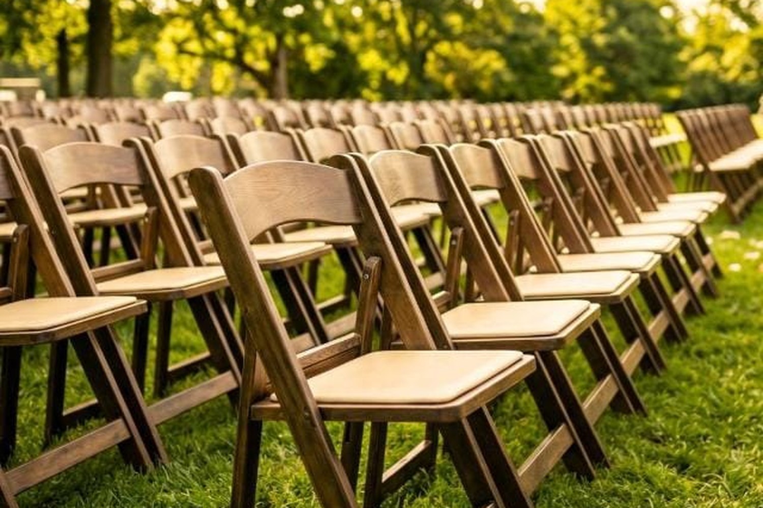 Chestnut WoodGrain resin folding chairs set in rows on a lawn at golden hour