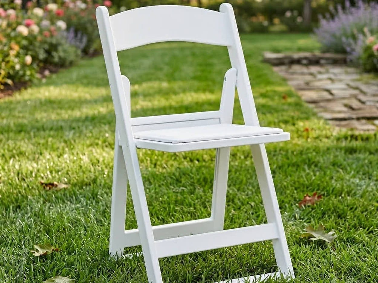 **[White Grass and Sand Series](https://chivari.com/products/white-grass-and-sand-series-resin-folding-chair-with-white-vinyl-cushion-and-stainless-steel-hardware)** on turf. Same 850-lb resin chair as the SuperResin™, with the foot geometry changed and stainless hardware instead of plated.
