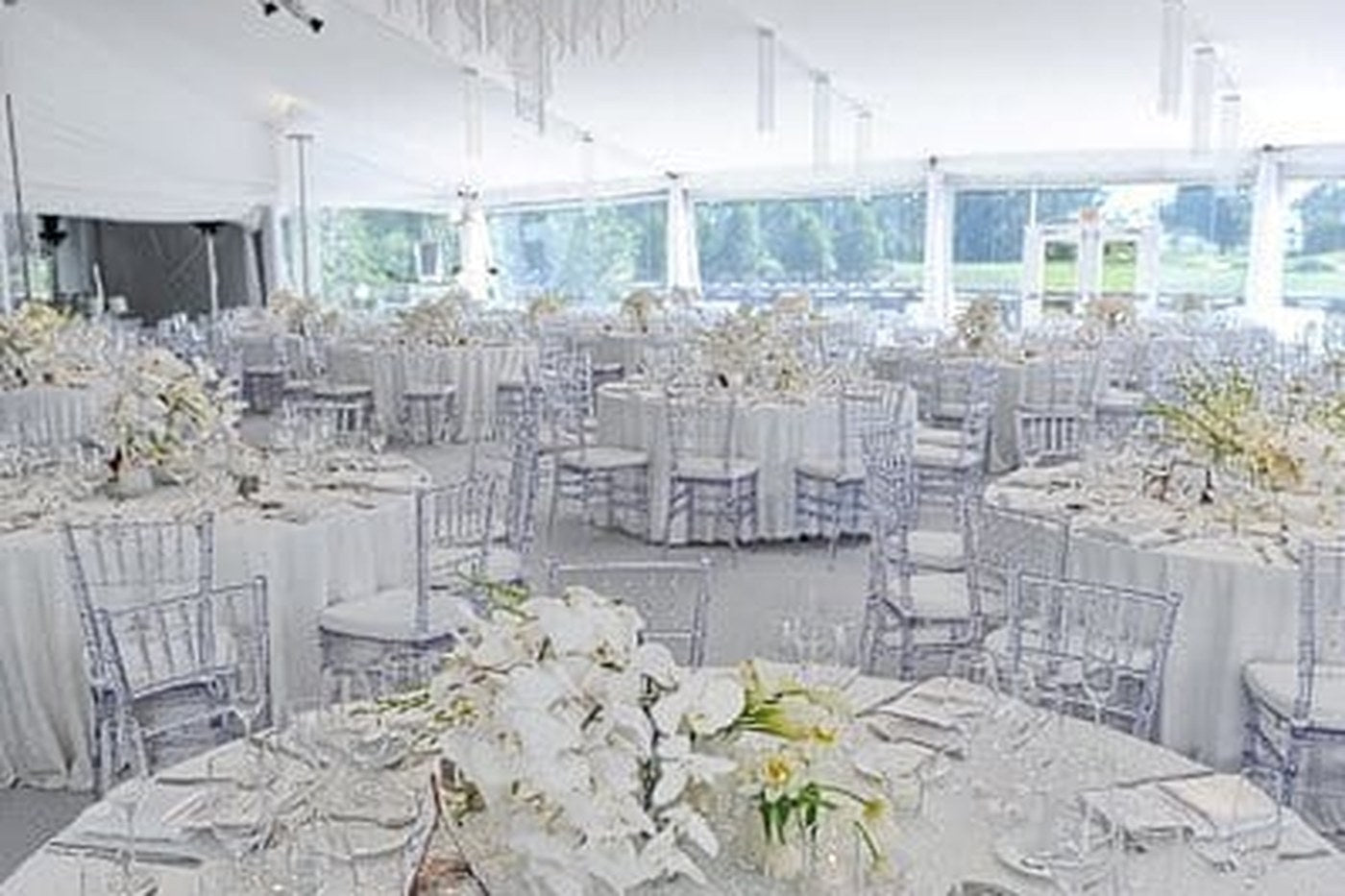 Overhead view of a large white reception with clear Chiavari chairs and round tables