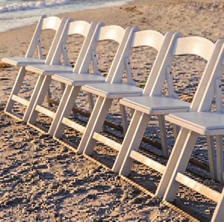 A row of white Grass & Sand chairs standing level on beach sand