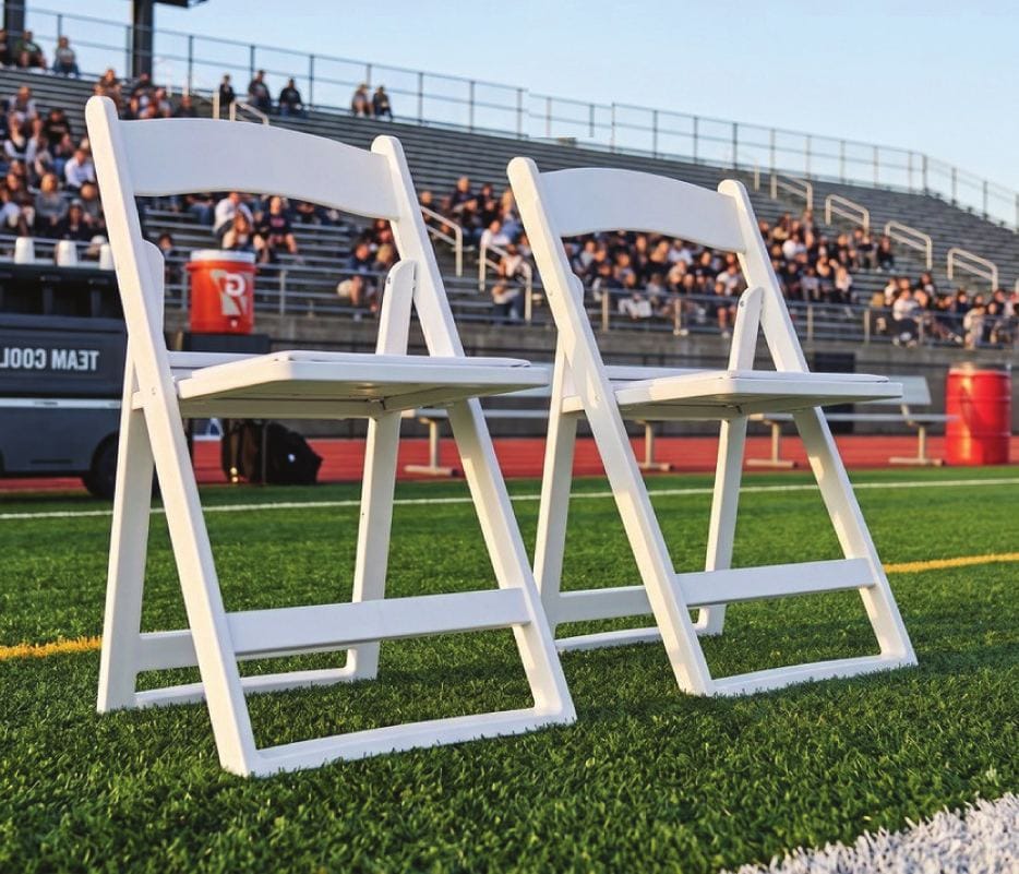 Two white Grass & Sand chairs on artificial turf at a stadium